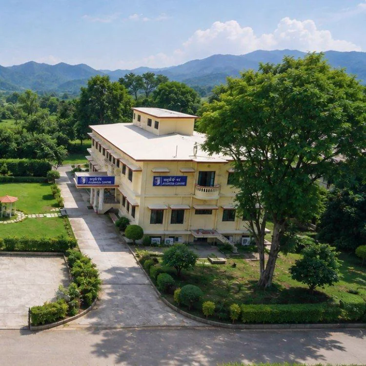 Aerial view of the Ayurveda Centre building among gardens and trees, with the Himalayan foothills behind