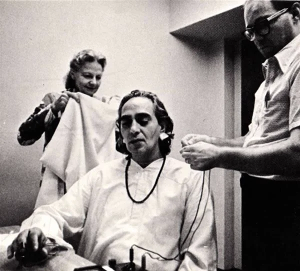 Swami Rama being prepared for a laboratory study of meditation, with researchers attaching sensors